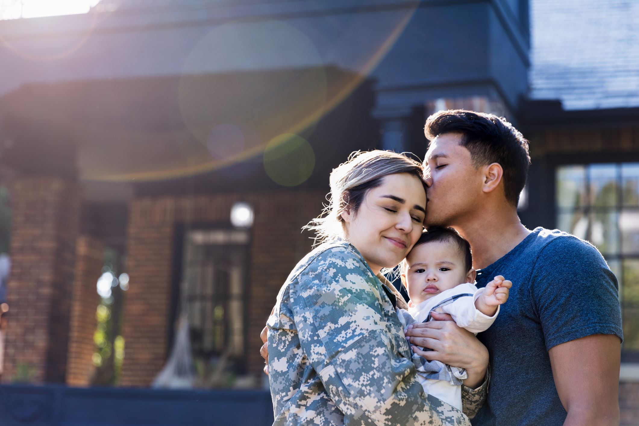 Military family hugging with dad, mom and young child