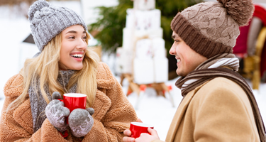 2 people dressed in winterwear holding mugs